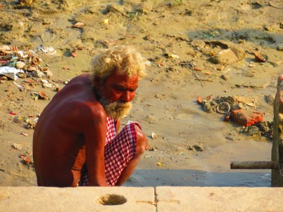 An old man waits at the river's edge, Varanasi, India