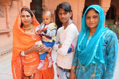 Two Indian women in brightly coloured saris, a young Indian man and a baby