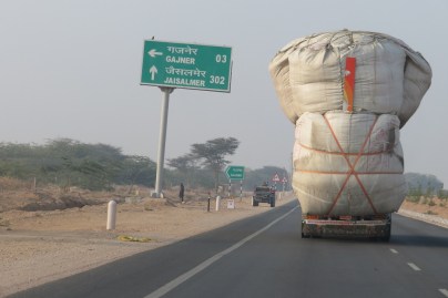 A large truck is overloaded with stock feed