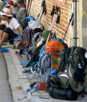 A row of backpacks leaning up against a brick wall