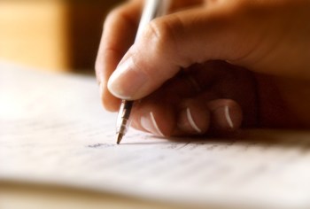 A woman's hand writing on a page with a ball point pen
