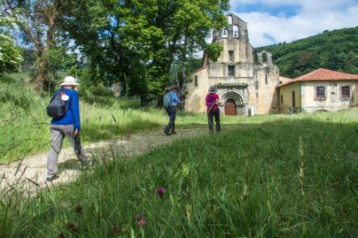 People walk past old buildings on the Camino Primitivo in Spain