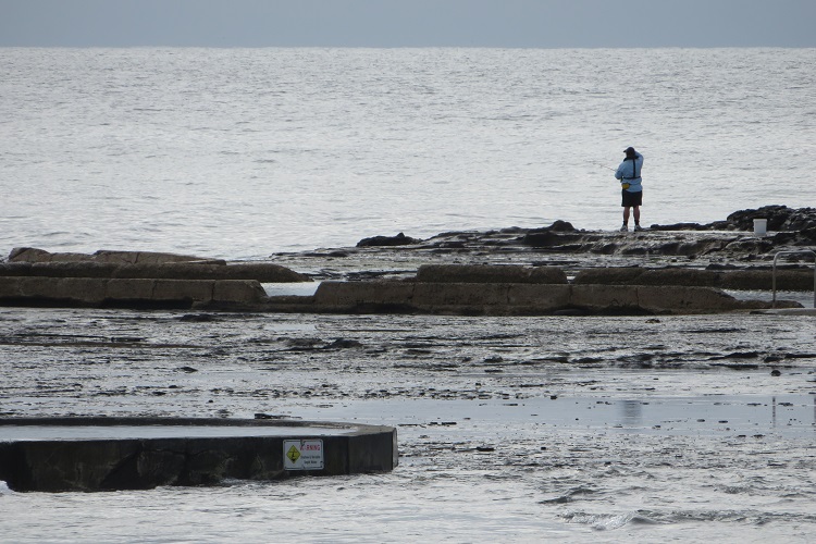 A lone fisherman on some rocks along the Kiama Coast Walk
