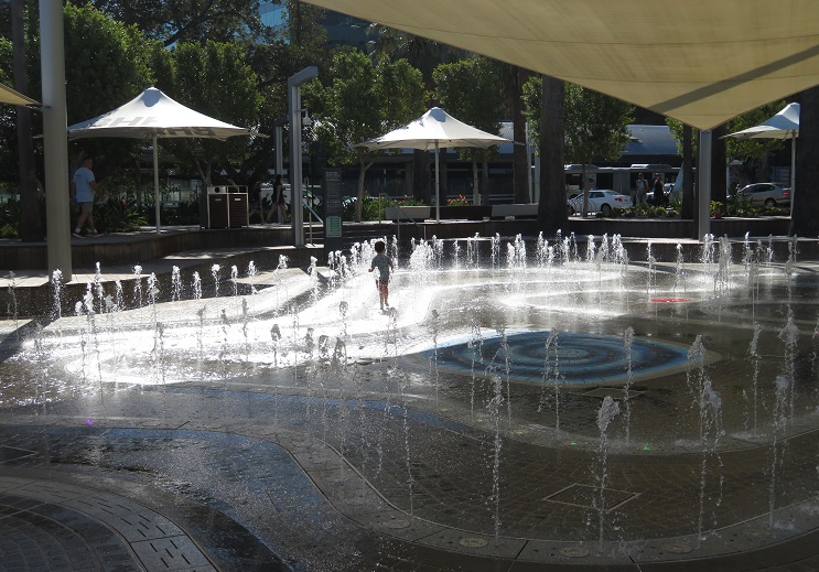A child runs and frolics in the water park at Elizabeth Quay
